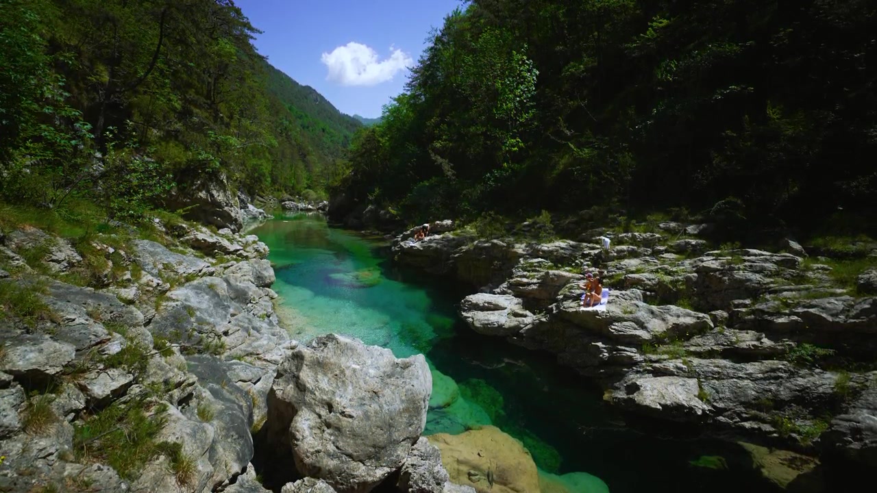 Fiume di montagna limpido verde smeraldo con turisti estivi che riposano alle Pozze Smeraldine. Dolomiti, Italia.