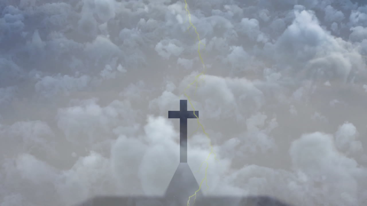 Silhouetted church steeple with cross against dramatic cloudy sky at sunset