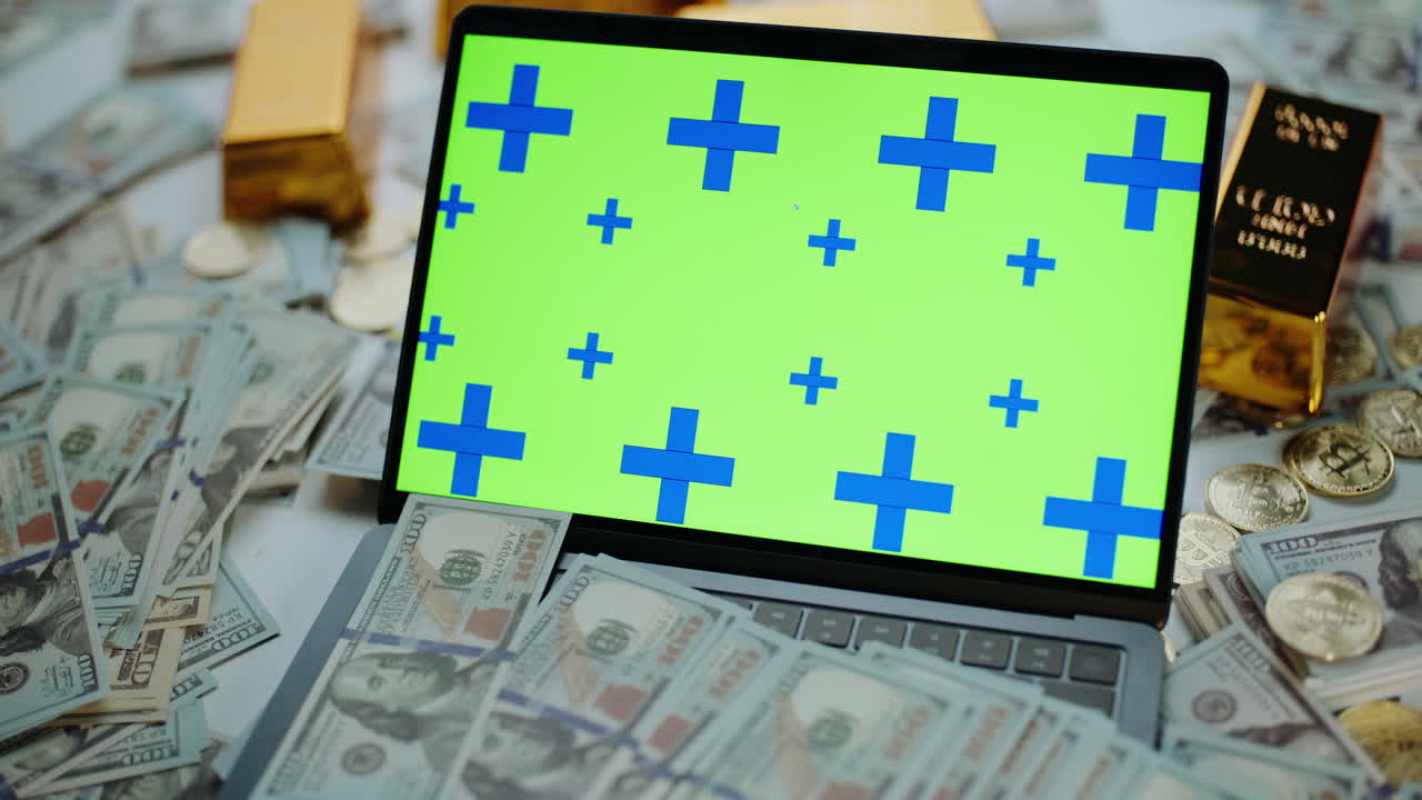 Laptop surrounded by money and gold