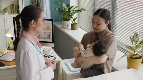 doctor examining a baby with its mother in a clinic