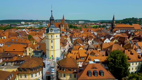 4k aerial drone video of the clock tower, st. johannis kirche church, and kirche st. gumbertus church in ansbach, germany with windmill in the distance
