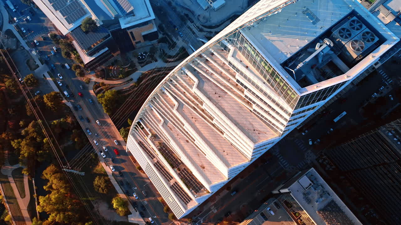 Vista aérea de arquitectura moderna en Austin. Perspectiva a vista de pájaro de un edificio de cristal contemporáneo con paneles solares en la azotea y tráfico urbano.