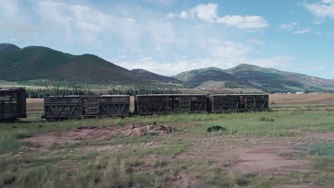 paning sot of an abandoned wood train with green mountains in the background