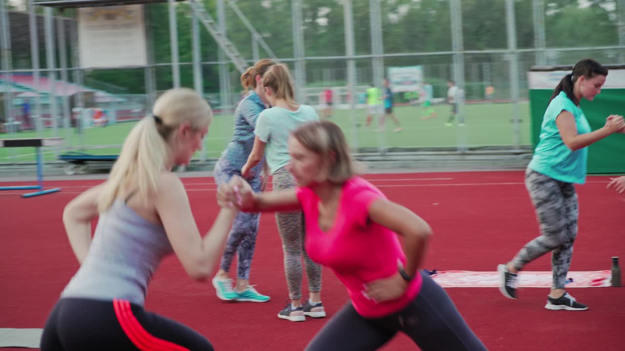 Athletic group training on stadium. Fitness instructor with people exercising in outdoor
