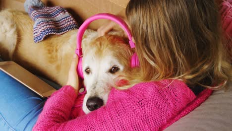 woman mounting headphone on dogs ear on sofa 4k