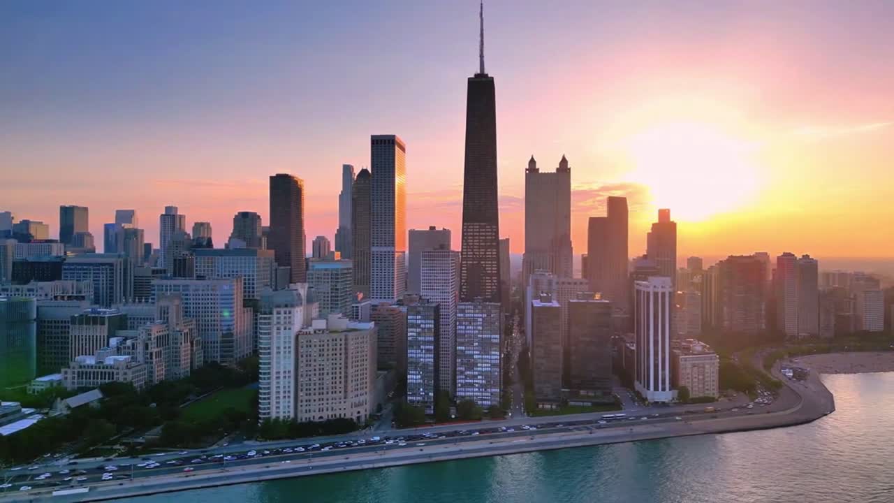 Una panoramica aerea con drone di Chicago che mostra il suo iconico skyline dall'alto. Grattacieli imponenti, il fiume serpeggiante e l'audace architettura della città si fondono in una visione dinamica e cinematografica del W