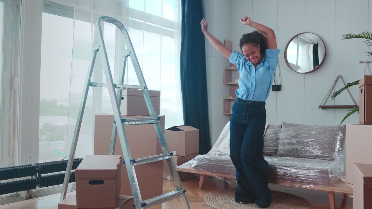 행복한 젊은 아프리카계 미국인 여성이 아파트로 이사한 후 기으로 춤을 춘다.
