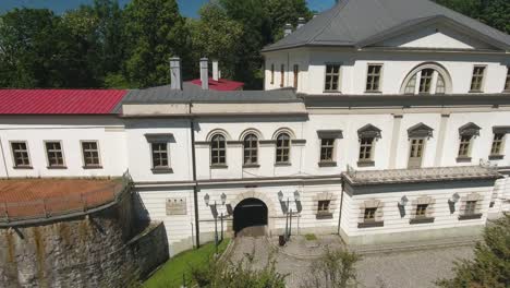 Ein-Historischer-Und-Restaurierter-Weißer-Palast-Im-Stadtzentrum,-Im-Sommer-In-Polen,-Aufgenommen-In-Einer-Dynamischen-4K-Drohnenaufnahme