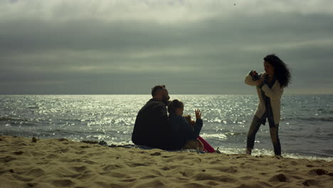 people enjoy beach photosession together at sea. family taking camera pictures.