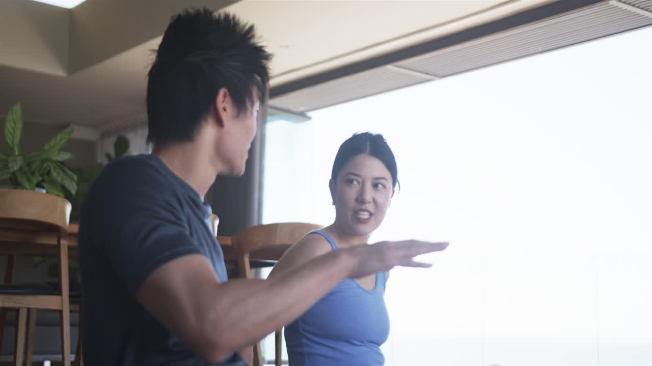 Vertical video: Man talking and gesturing, woman moving bottle while replying, health icons showing