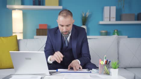 the businessman in a suit is frustrated by what he sees on the laptop.