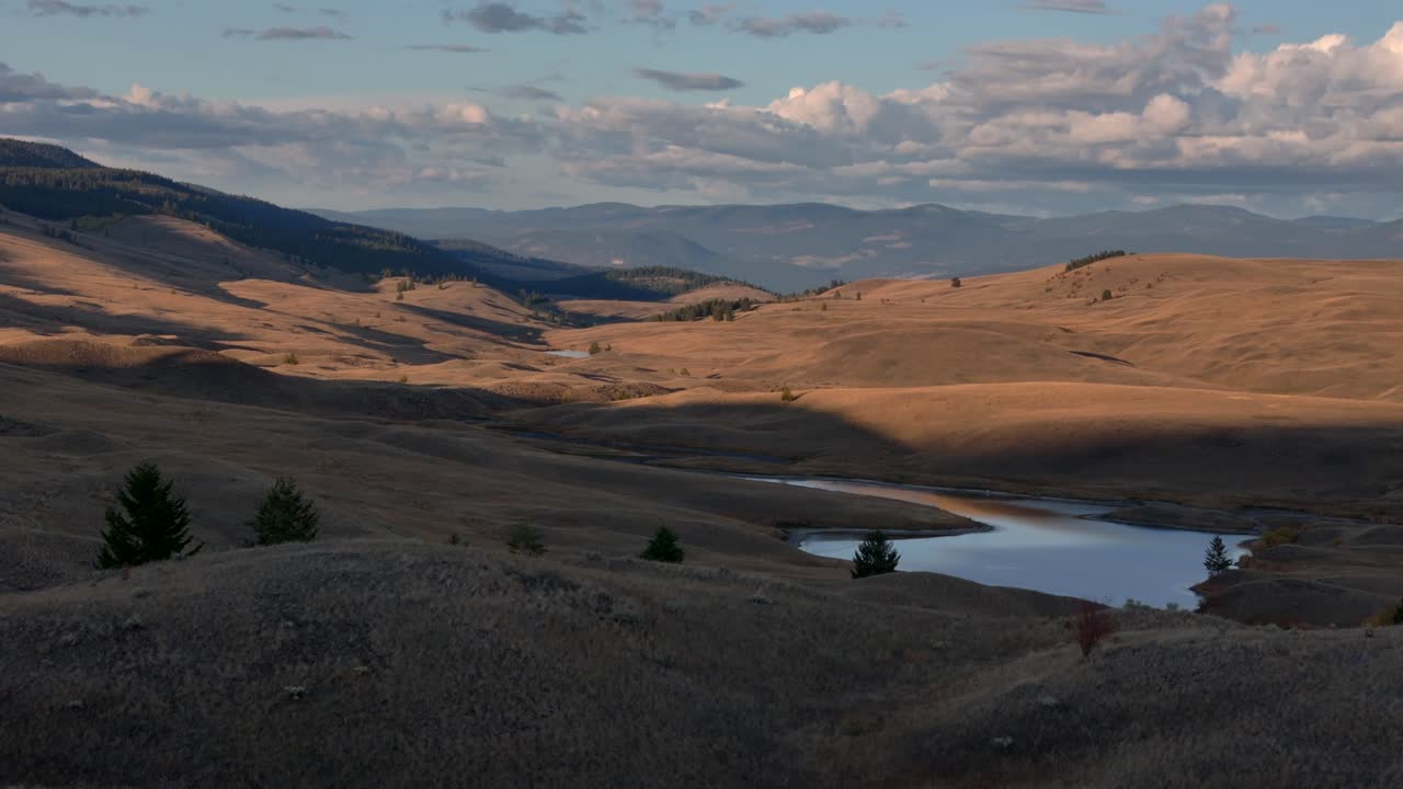 Aerial Symphony at Dusk: Grassland, Lake, and Forested Mountains in Sunset's Glow