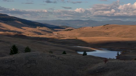 Aerial-Symphony-at-Dusk:-Grassland,-Lake,-and-Forested-Mountains-in-Sunset's-Glow