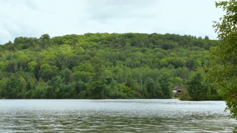 timelapse - clouds stir over forested hill and choppy lake