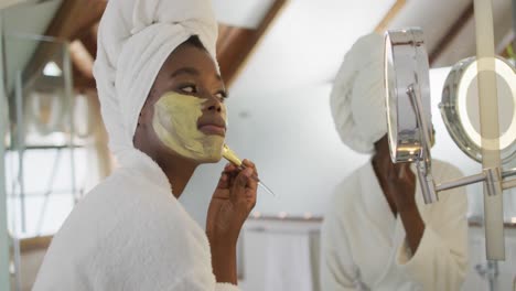 african american attractive woman applying face mask in bathroom