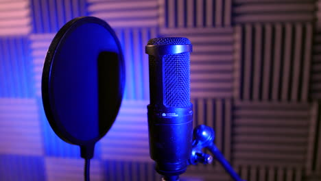 un micrófono de condensador de estudio profesional en una cabina de grabación de voz sobre un soporte con escudo pop