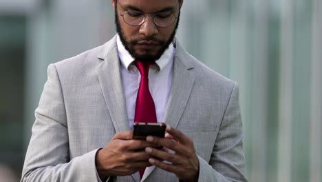Focused-businessman-using-smartphone-during-stroll