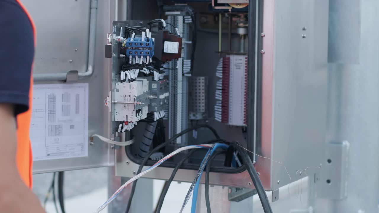 전기 엔지니어가 장비 제어 캐비에서 전기 시스템을 검사합니다.