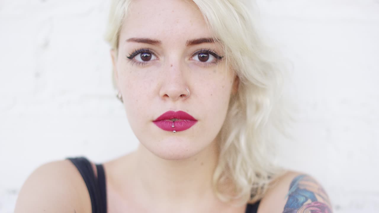 серьезная молодая блондинка смотрит в камеру.