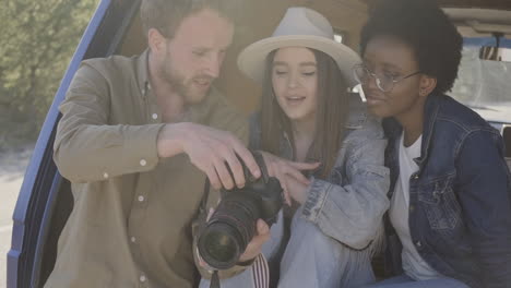 un joven fotógrafo muestra las fotografías que ha tomado a dos hermosas jóvenes dentro de la caravana durante un viaje por carretera 3