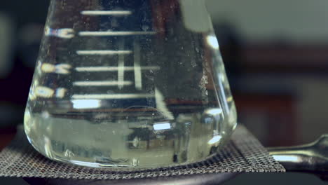 close up of water beginning to boil in the bottom of an erlenmeyer flask