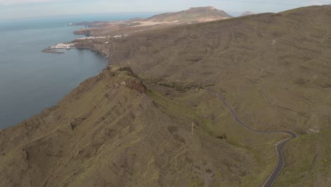 Panorama-drone-shot-of-a-mountain-and-a-curvy-street-on-the-coast