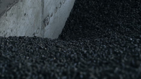 heap of pressed charcoal moving downward into the furnace. small pieces of pressed charcoal going down at the cement wall. close up.