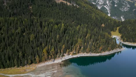 imagem de drone da beira do lago obernberger, no tirol, na áustria, com água azul muito clara e reflexos das montanhas.