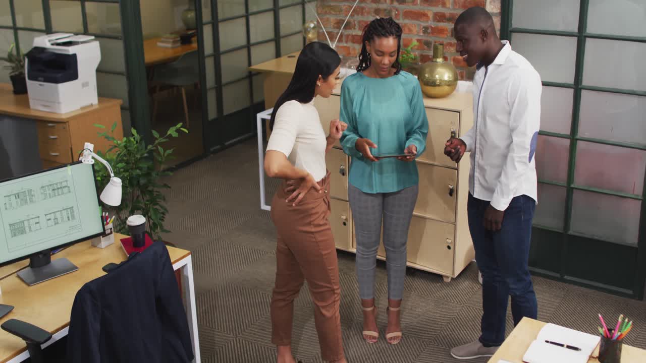 arquitectos diversos felices usando tableta y discutiendo el trabajo en la oficina