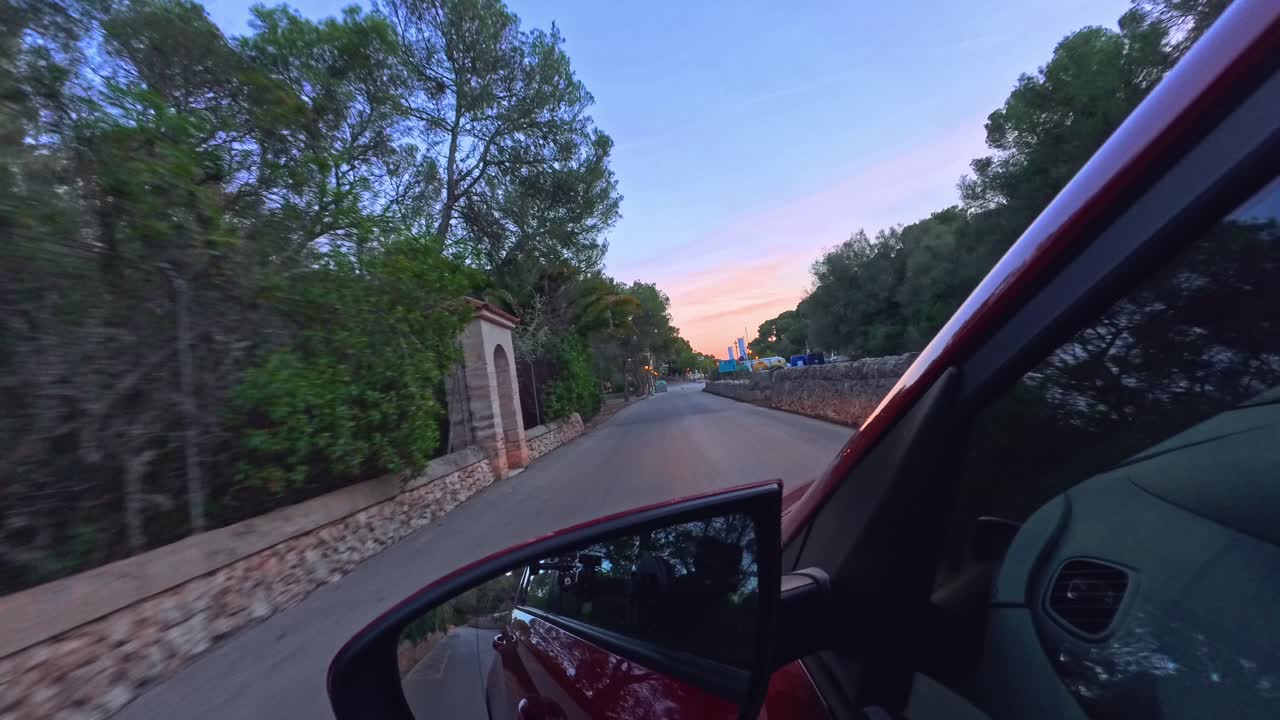 pov del espejo izquierdo de un coche que conduce por la carretera durante la hora dorada en palma de mallorca