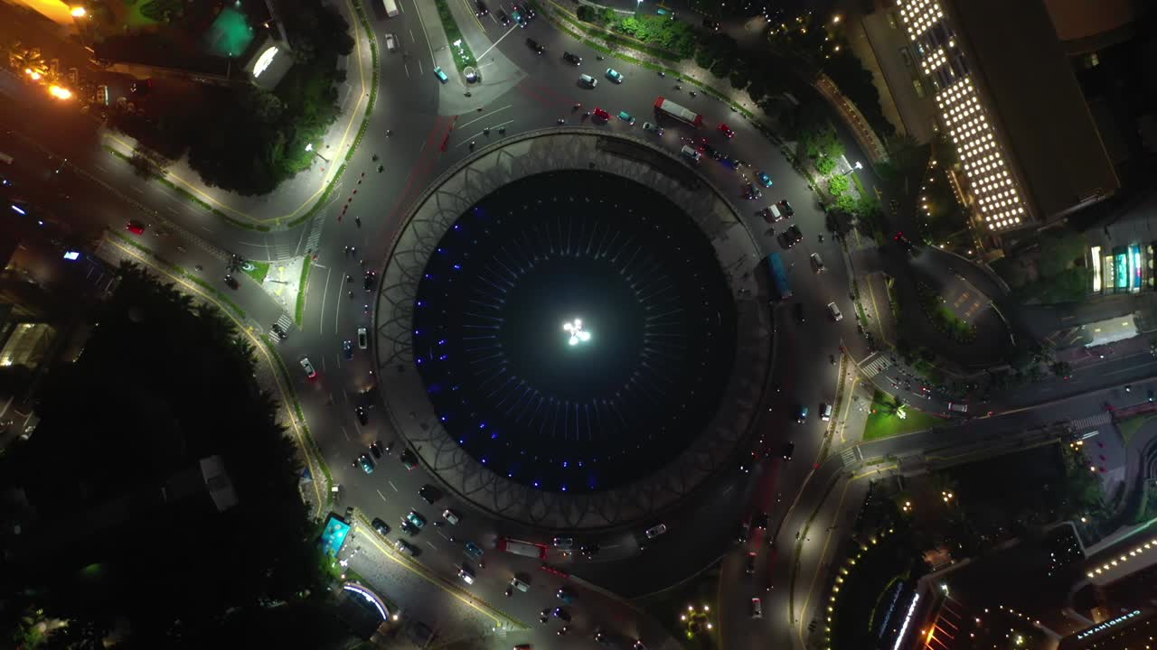 orario notturno illuminato centro città di jakarta traffico circolo stradale fontana aerea topdown panorama 4k indonesia