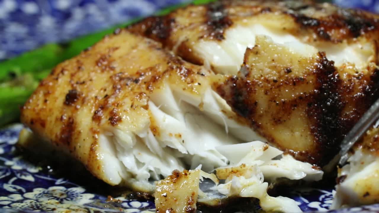 totuava totoaba fish dish cut by fork in restaurant