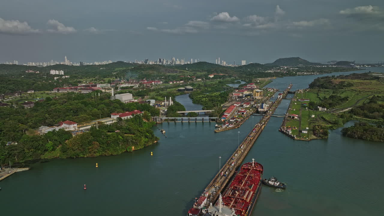 antena v32 de la ciudad de panamá que establece el sobrevuelo de drones en el lago miraflores con un buque de carga que transita en las esclusas del canal con el paisaje urbano del centro en el fondo - filmado con el cine mavic 3 - marzo de 2022