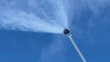 Low-angle-view-of-snow-maker-spraying-fresh-powder-on-a-sunny-day