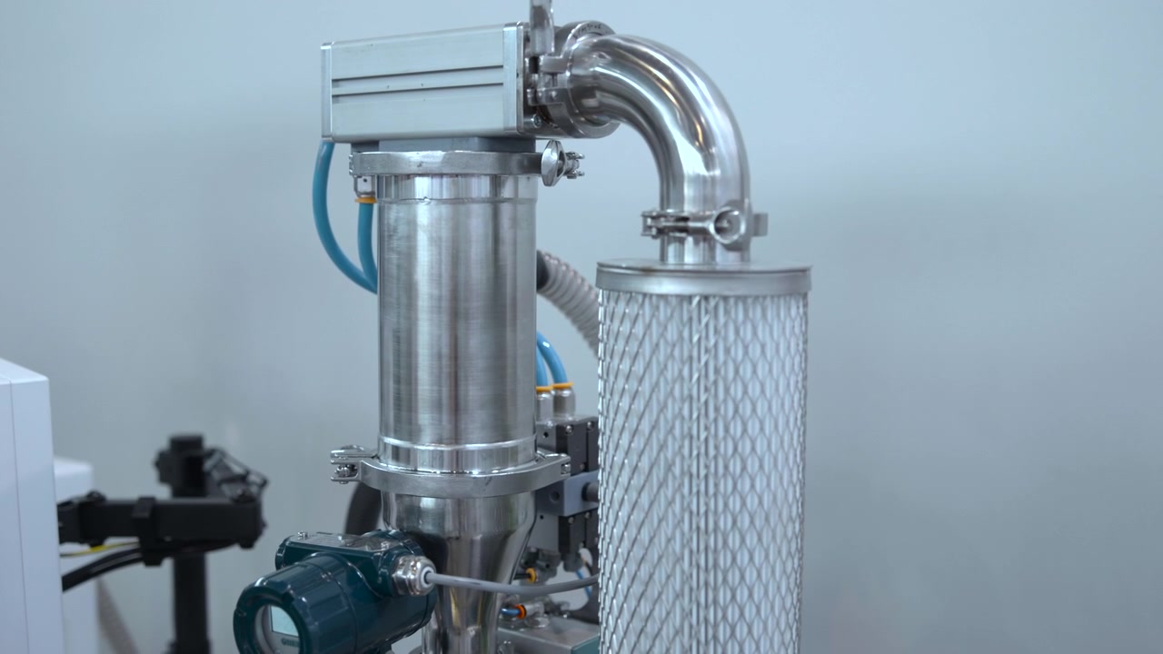 a detailed side view of industrial equipment in a laboratory or industrial setting, featuring metallic cylinders, pipelines, and valves. the scene has a neutral and technical mood.