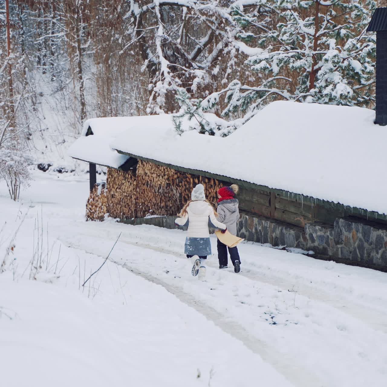 A little boy and girl looked at the image on the envelope not far from the building and are running an ahead along the path near the winter forest.