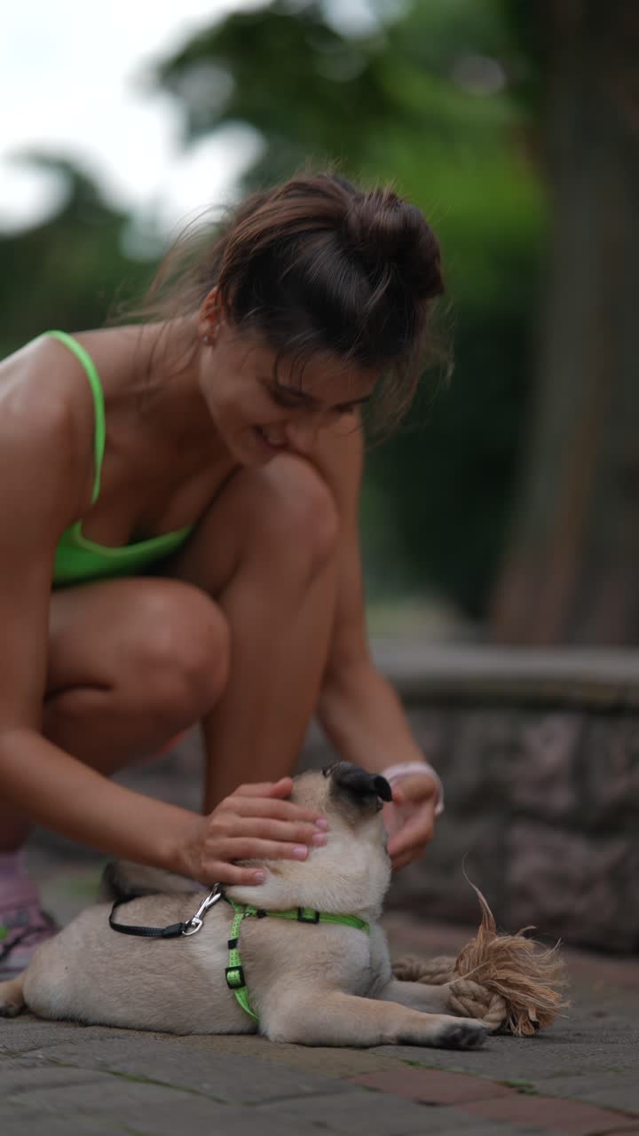 한 여자 가 공원 에서 파그 와 함께 놀고 있다