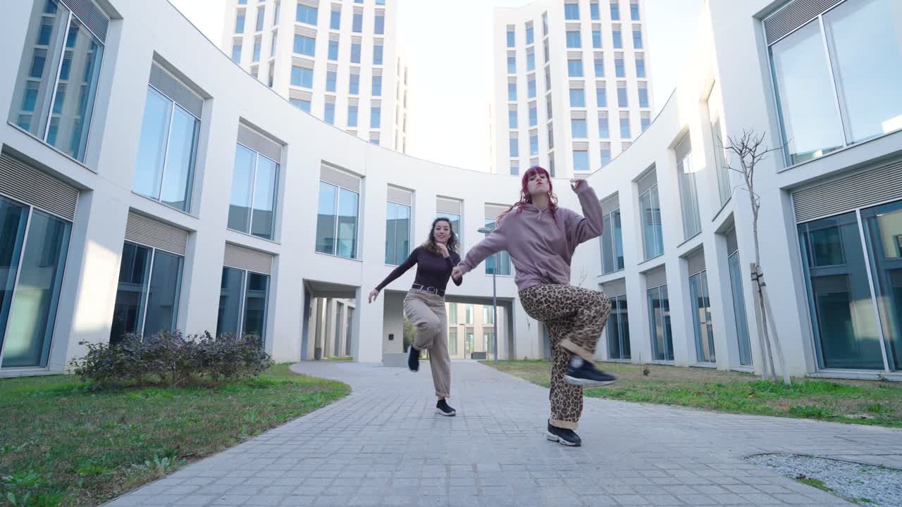 Young women dancing outside modern building