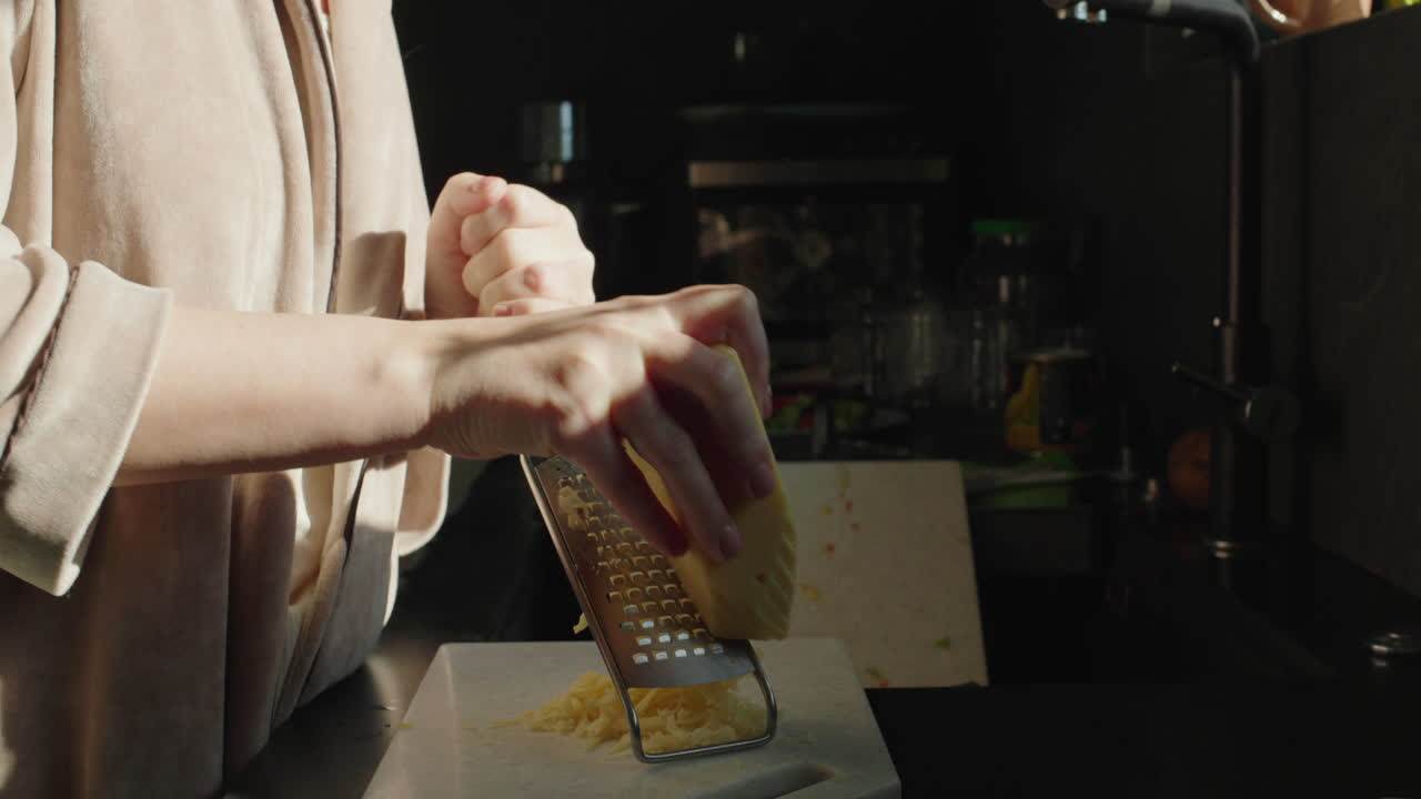mujer rastrillando queso en una cocina