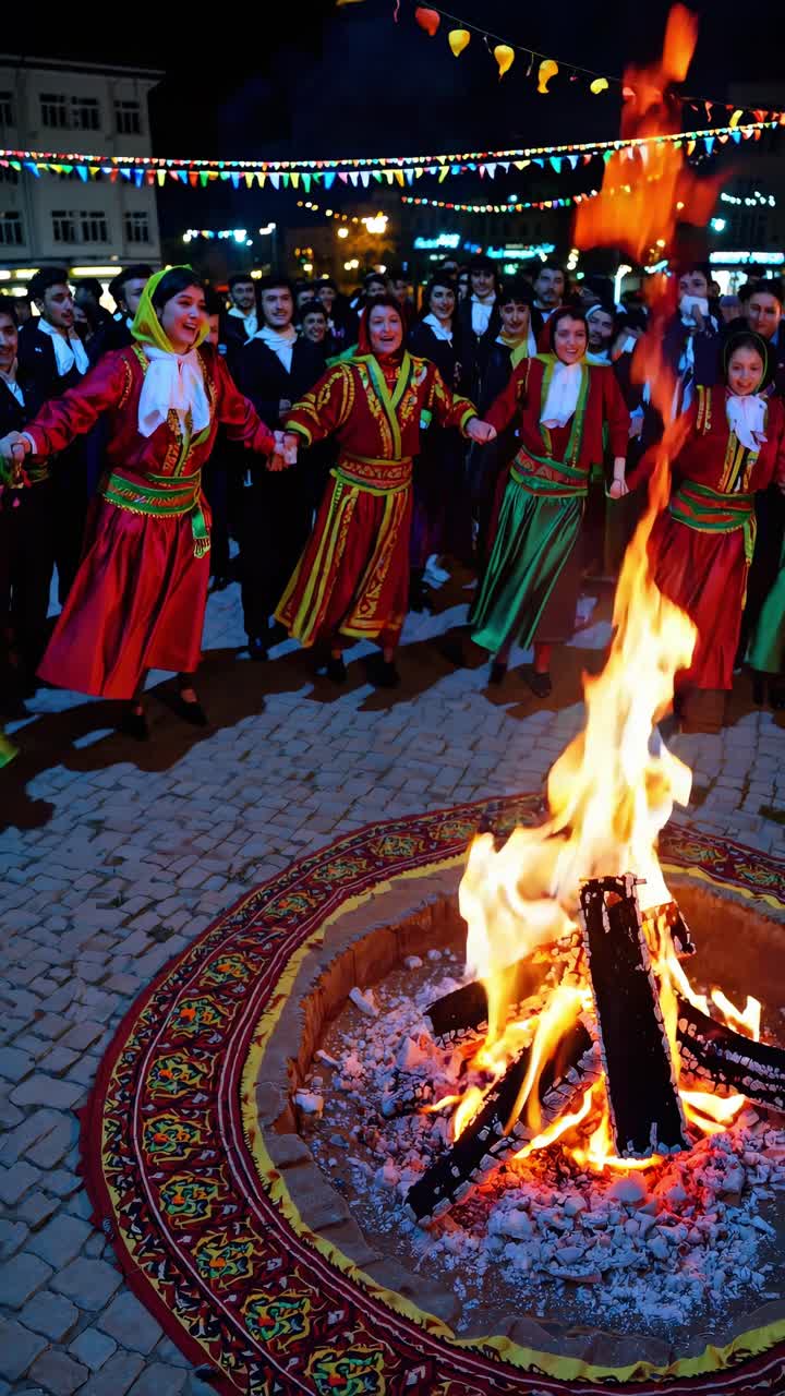 People wearing traditional attire dancing in circle around blazing bonfire, celebrating nighttime festival in festively decorated town square with colorful flags hanging overhead