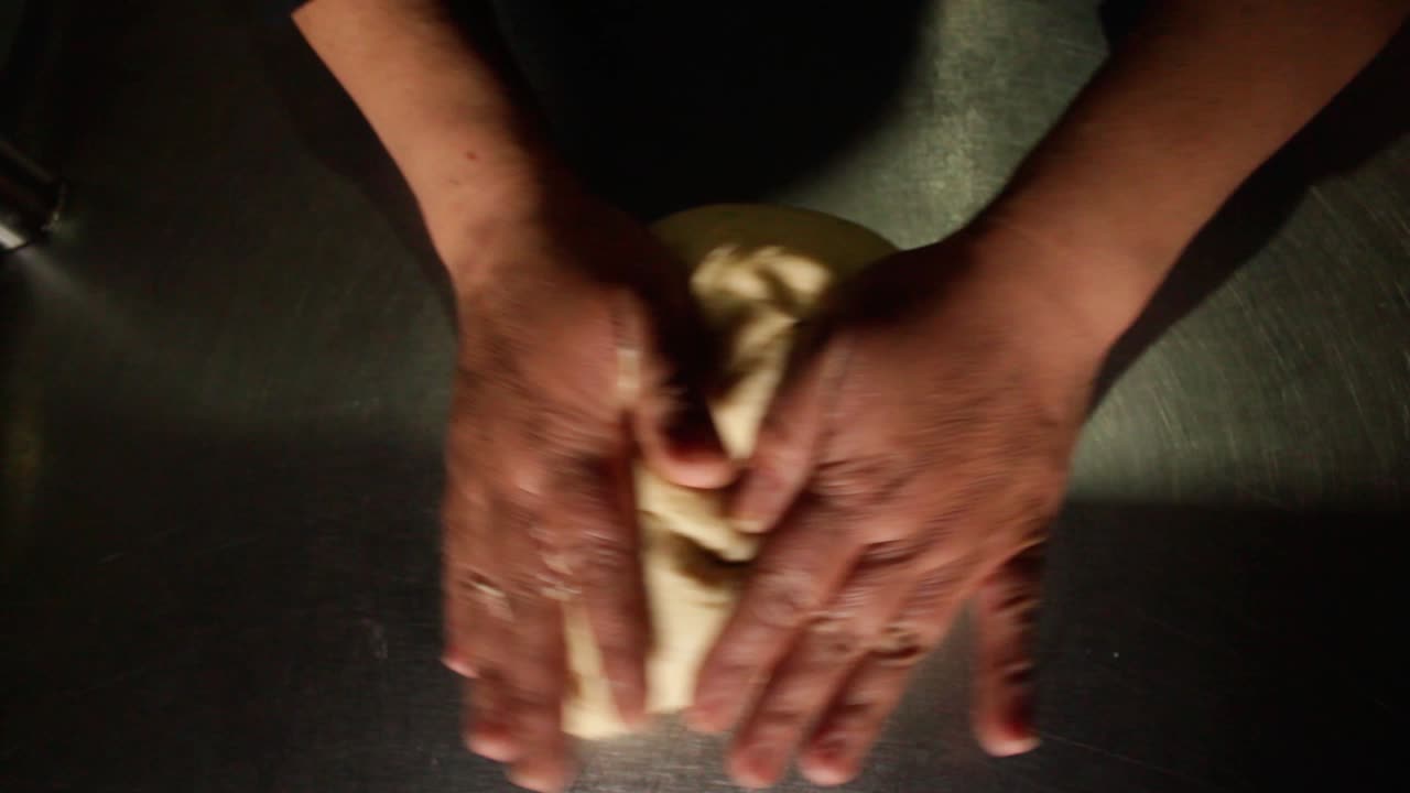 top view of a female chef deflate pizza dough