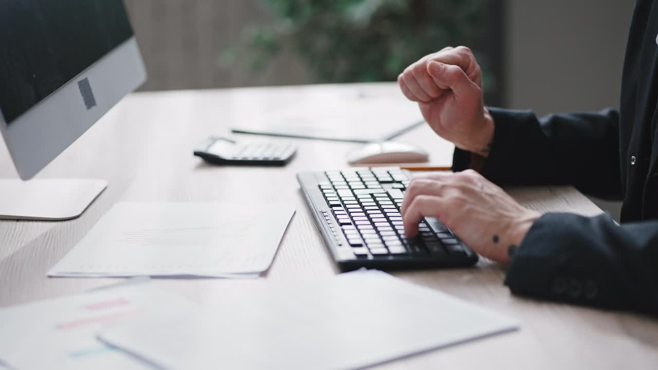 Business moderno. Uomo d'affari irriconoscibile che digita un rapporto sulla tastiera, confrontando dati su un dispositivo e grafici colorati