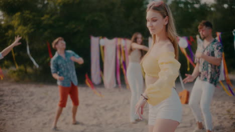 Beautiful-woman-grooving-against-friends-dancing-at-beach