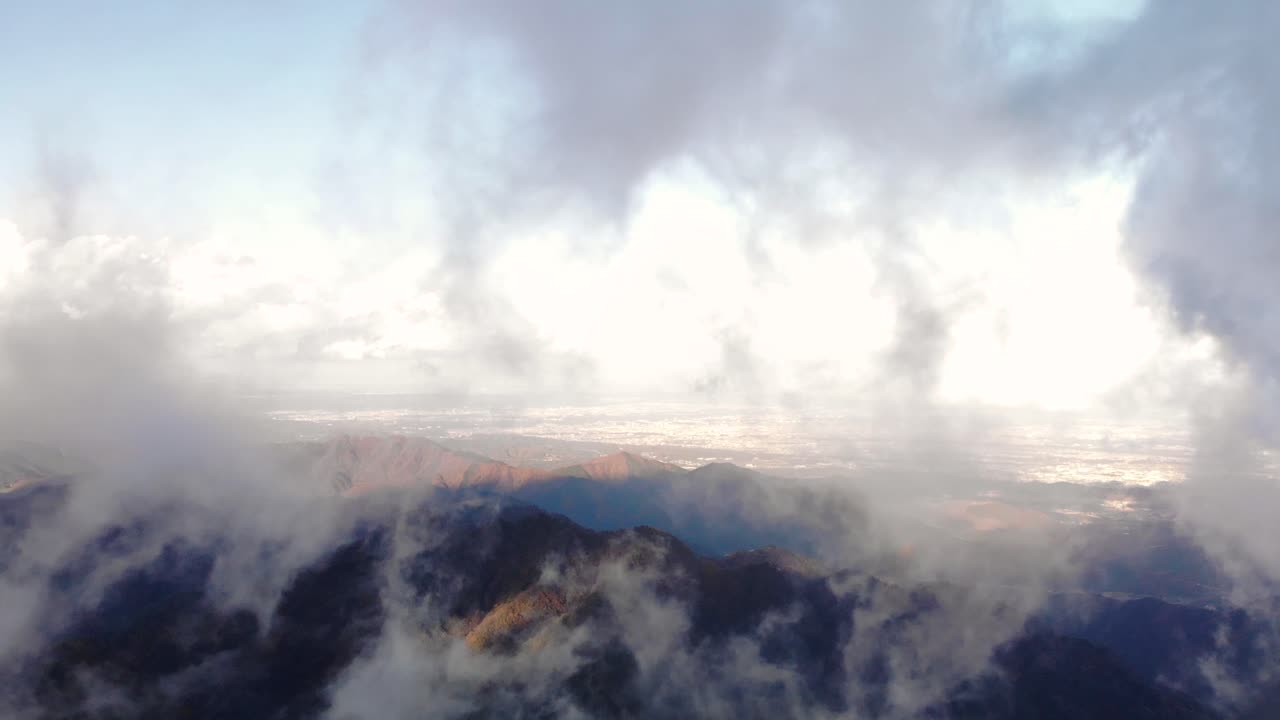 Scenic View Of Rocky Mountains Through The Clouds Soaring High On A Sunny Day - Aerial Shot