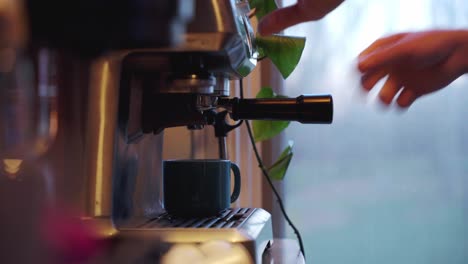 Caucasian-man-with-ring-amateur-barista-pulling-espresso-shot-near-window-tight-profile-silhouette