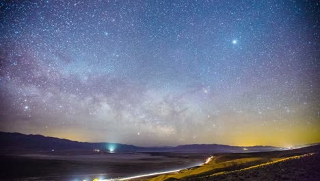 time lapse - milky way galaxy over mountain range with traffic - 4k