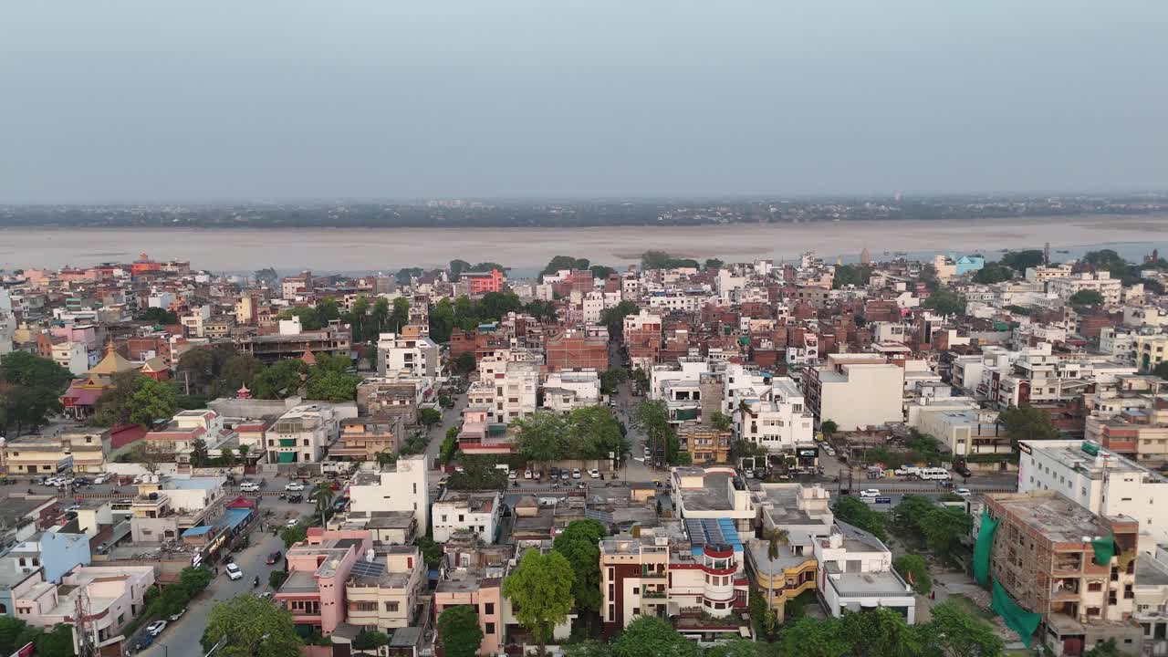 Panoramic drone shot of a city along a vast riverbank, illustrating a balance between natural water bodies and urban development
