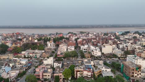 panoramic drone shot of a city along a vast riverbank, illustrating a balance between natural water bodies and urban development