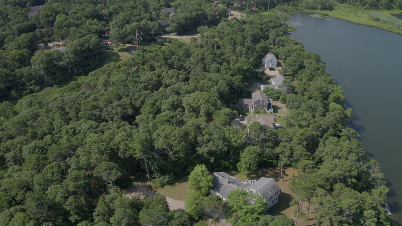 Dron se desplaza a la derecha sobre un hermoso paisaje en Cape Cod con casas y un estanque