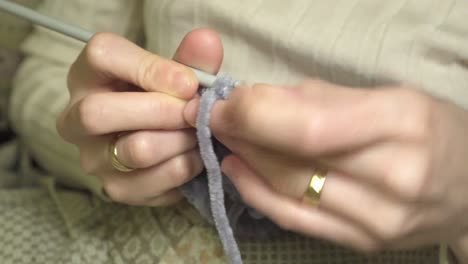 close-up of human hands crocheting with needles and wool knitting a small warm garment for the winter